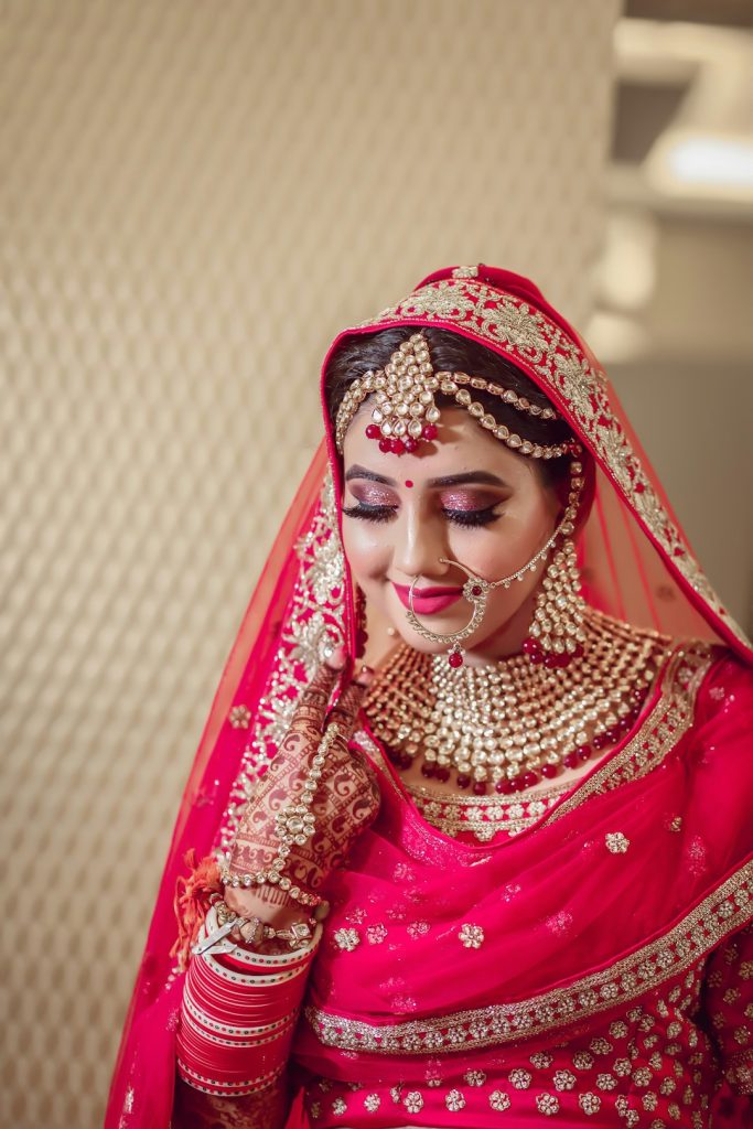 Bride in a red lehenga with gold jewellery and henna, lehenga captions for Instagram