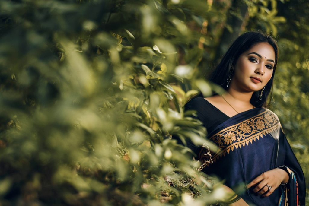 Woman in a saree standing among green plants, saree captions for Instagram