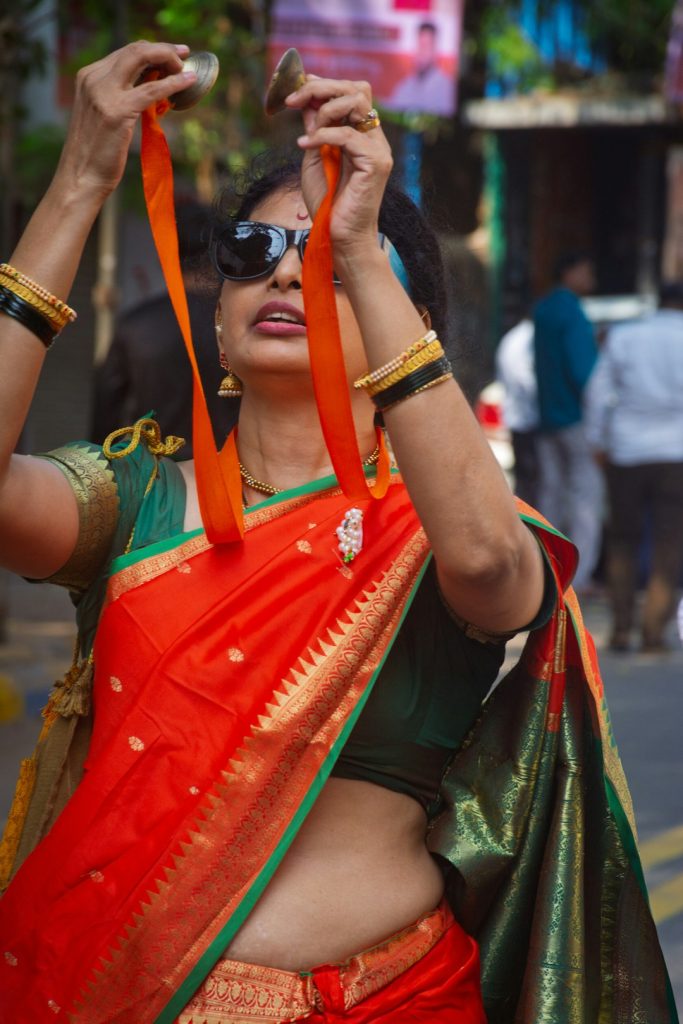 Woman in a red and green saree playing cymbals, Marathi saree captions